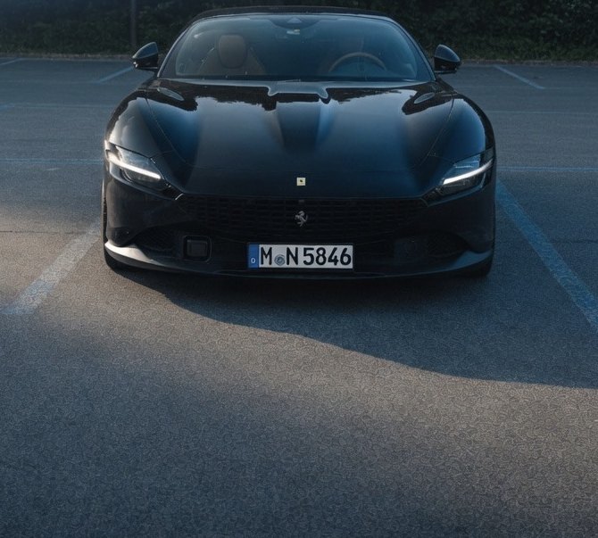 Supercar nera con i fari accesi all'imbrunire