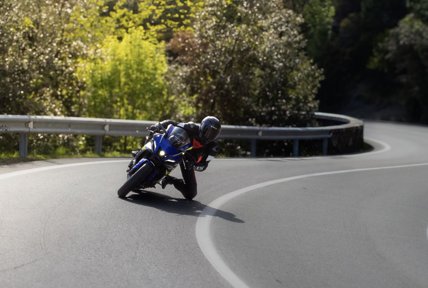 Moto blu in piega in un tornante tra il verde